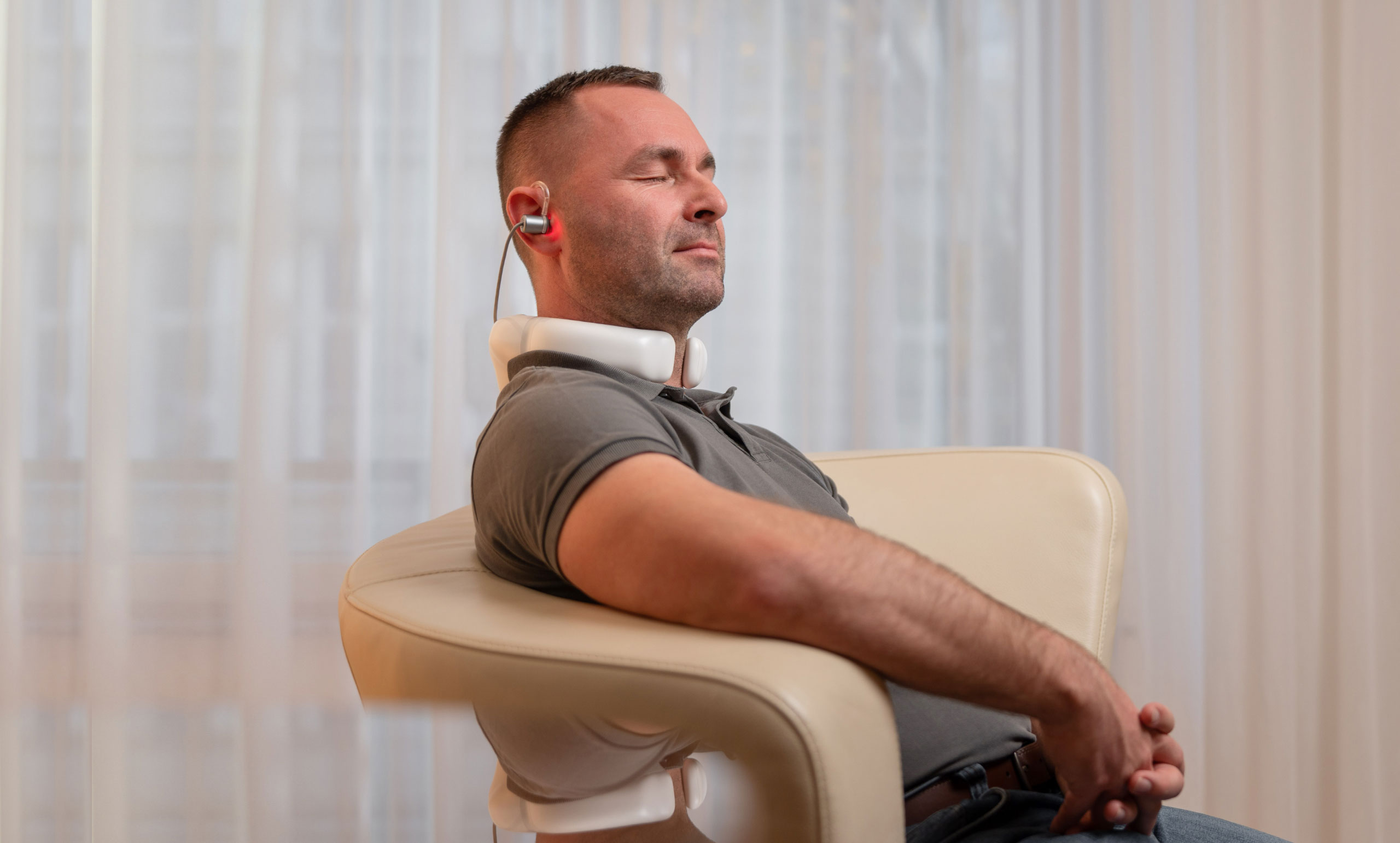 Mann mit LumoHome Lasertherapie am Ohr und Nacken