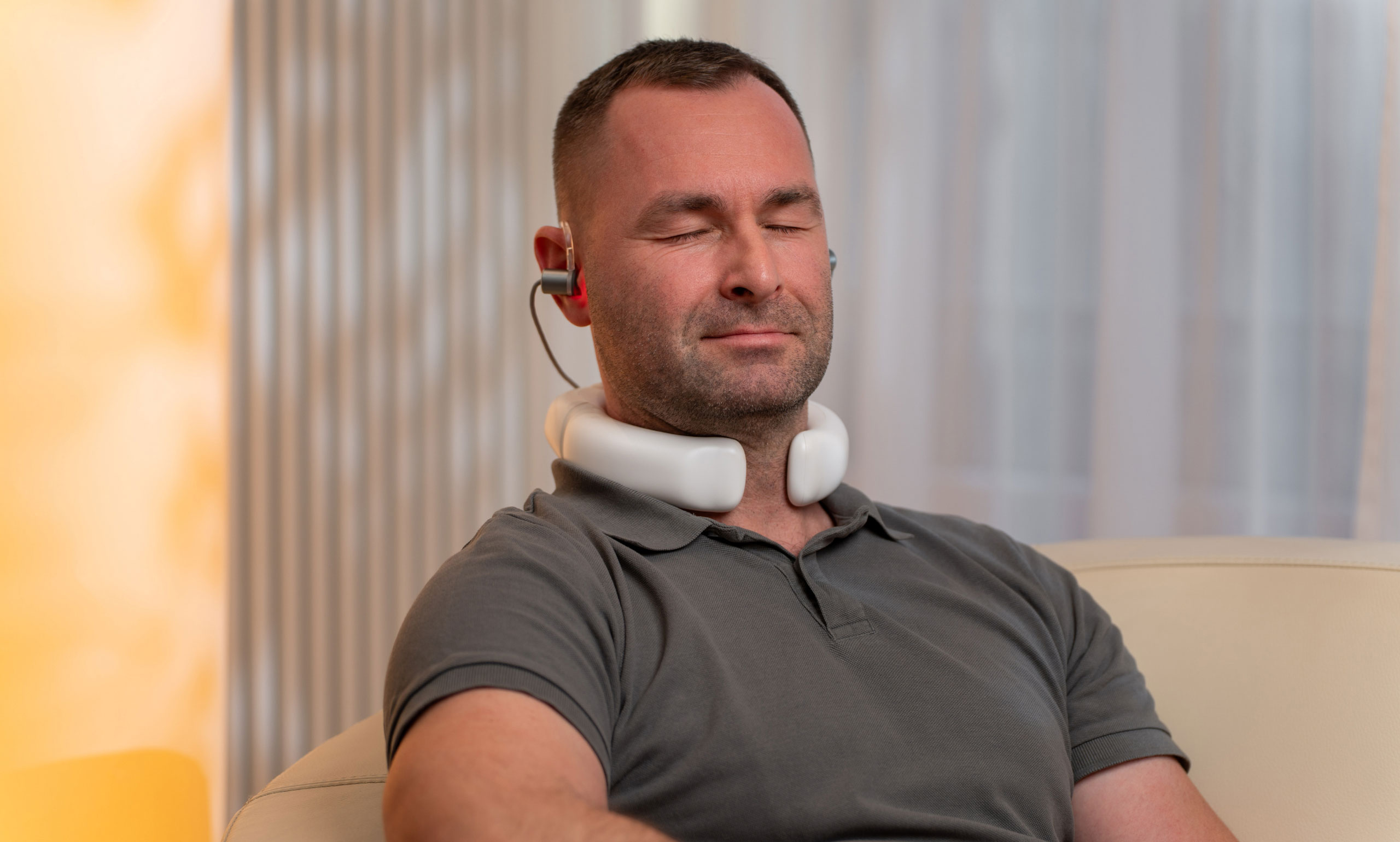 Mann mit LumoHome Lasertherapie am Ohr und Nacken