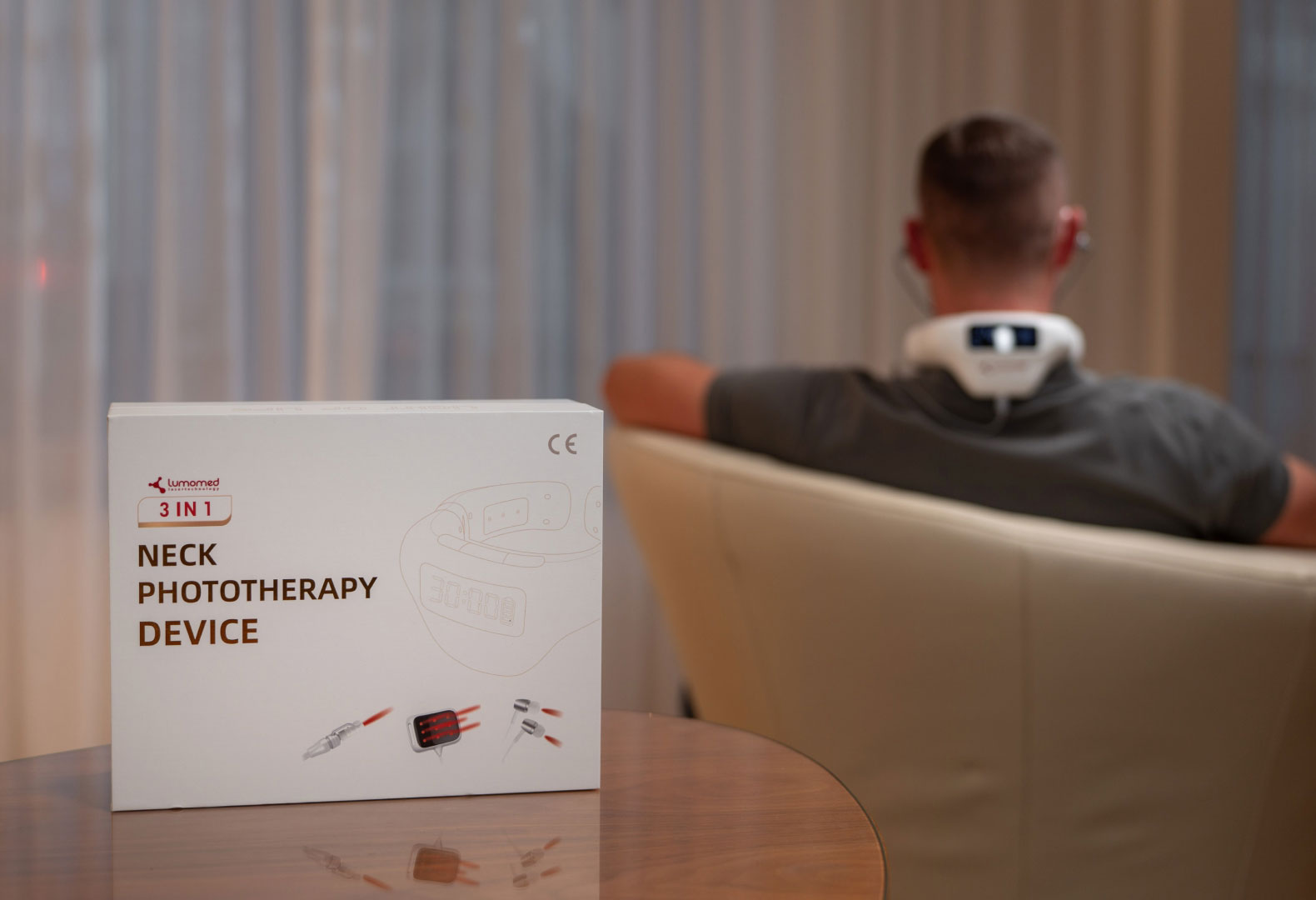 LumoHome Produktverpackung im Vordergrund, im Hintergrund eine Anwenderin mit aktiviertem Lasergerät