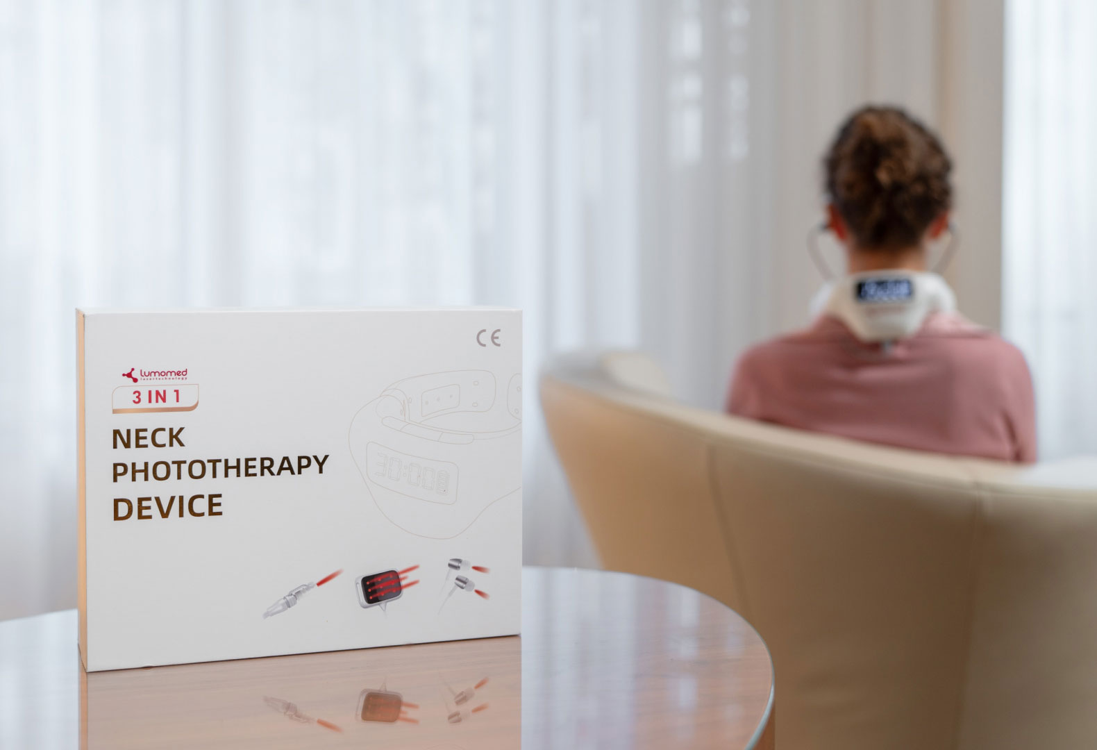 LumoHome Verpackung & Anwendung LumoHome Produktverpackung im Vordergrund, im Hintergrund eine Anwenderin mit aktiviertem Lasergerät