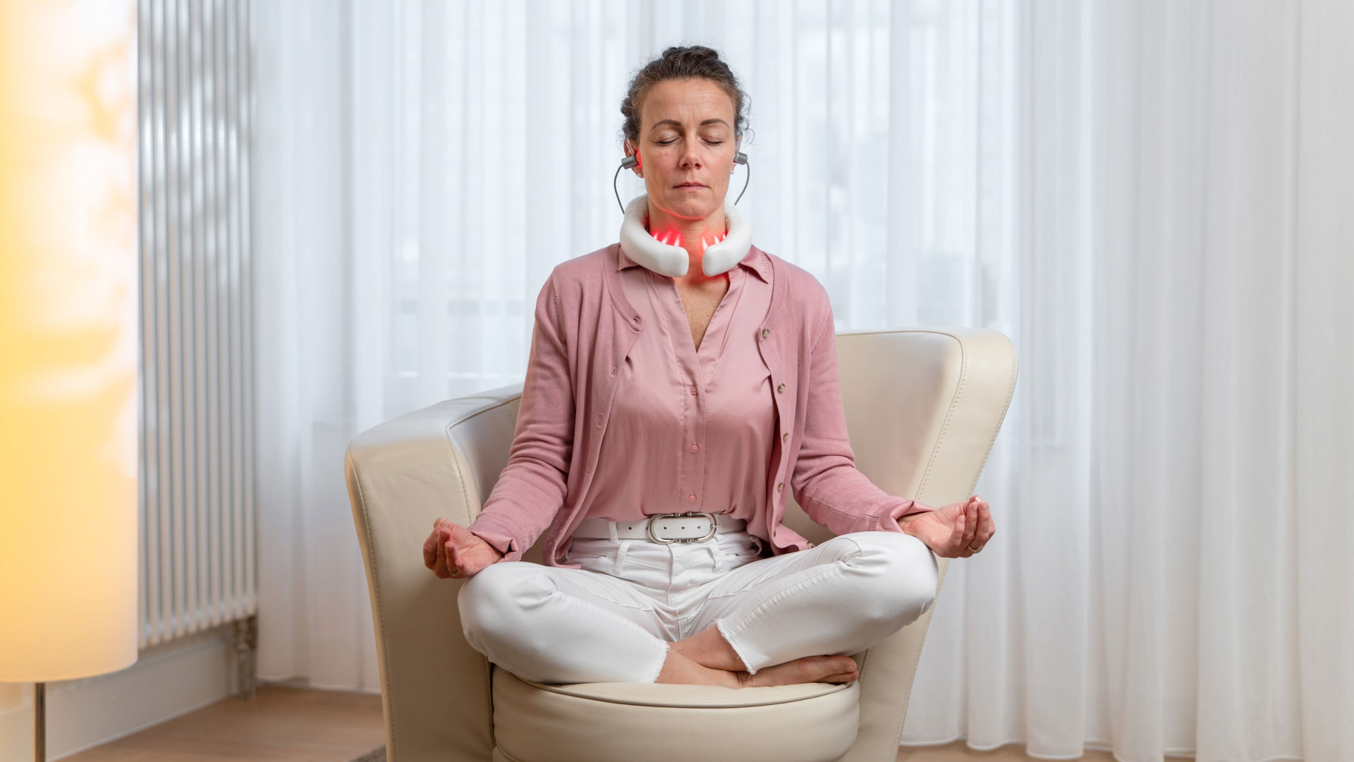Frau nutzt das LumoHome Lasertherapiegerät während einer entspannten Meditation